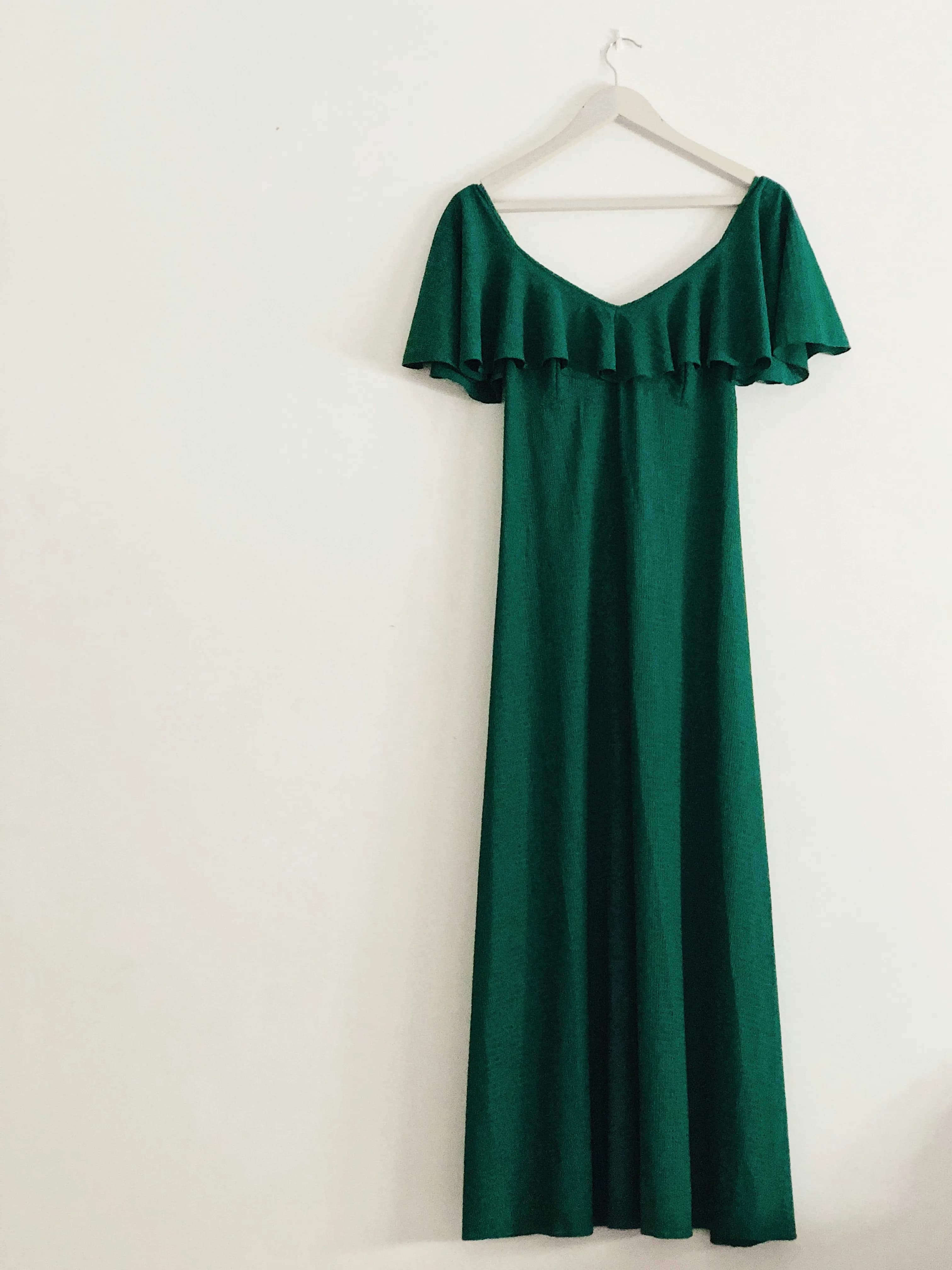 Original product photo of a green dress on a hanger against a plain background